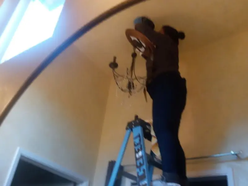 Electrician installing a chandelier in a South Whittier residence